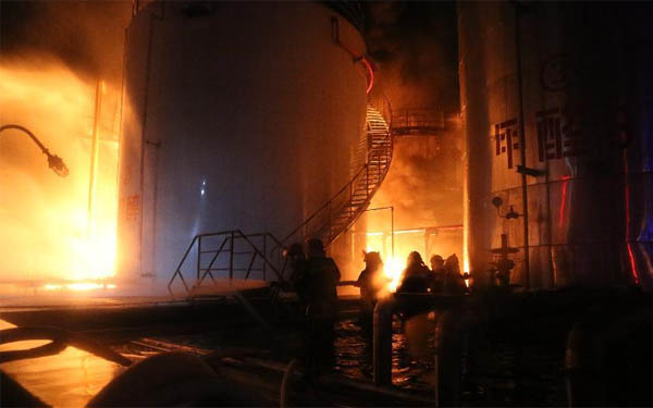 在發(fā)生火災(zāi)的儲(chǔ)罐區(qū),消防救援人員正在全力撲滅大火