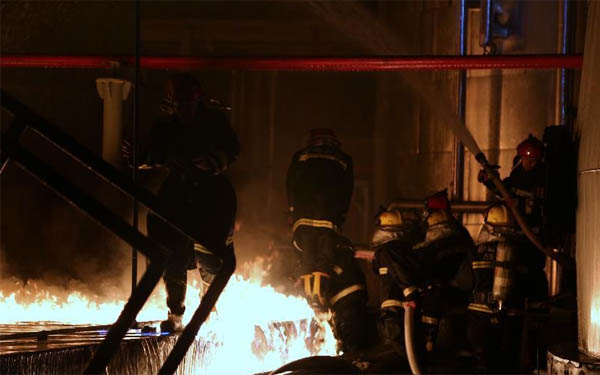 消防救援人員正在近距離對(duì)失火的儲(chǔ)罐區(qū)處理