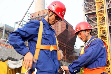 進(jìn)入高空作業(yè)前,同事正在幫他穿戴高空安全帶