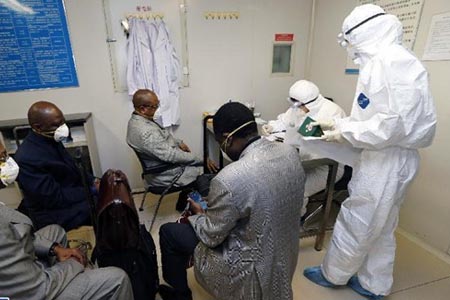 醫(yī)護(hù)人員穿戴埃博拉防護(hù)服、護(hù)目鏡及手套處理患者