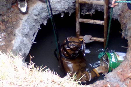 身穿防化服背空氣呼吸器對(duì)污水池進(jìn)行清理